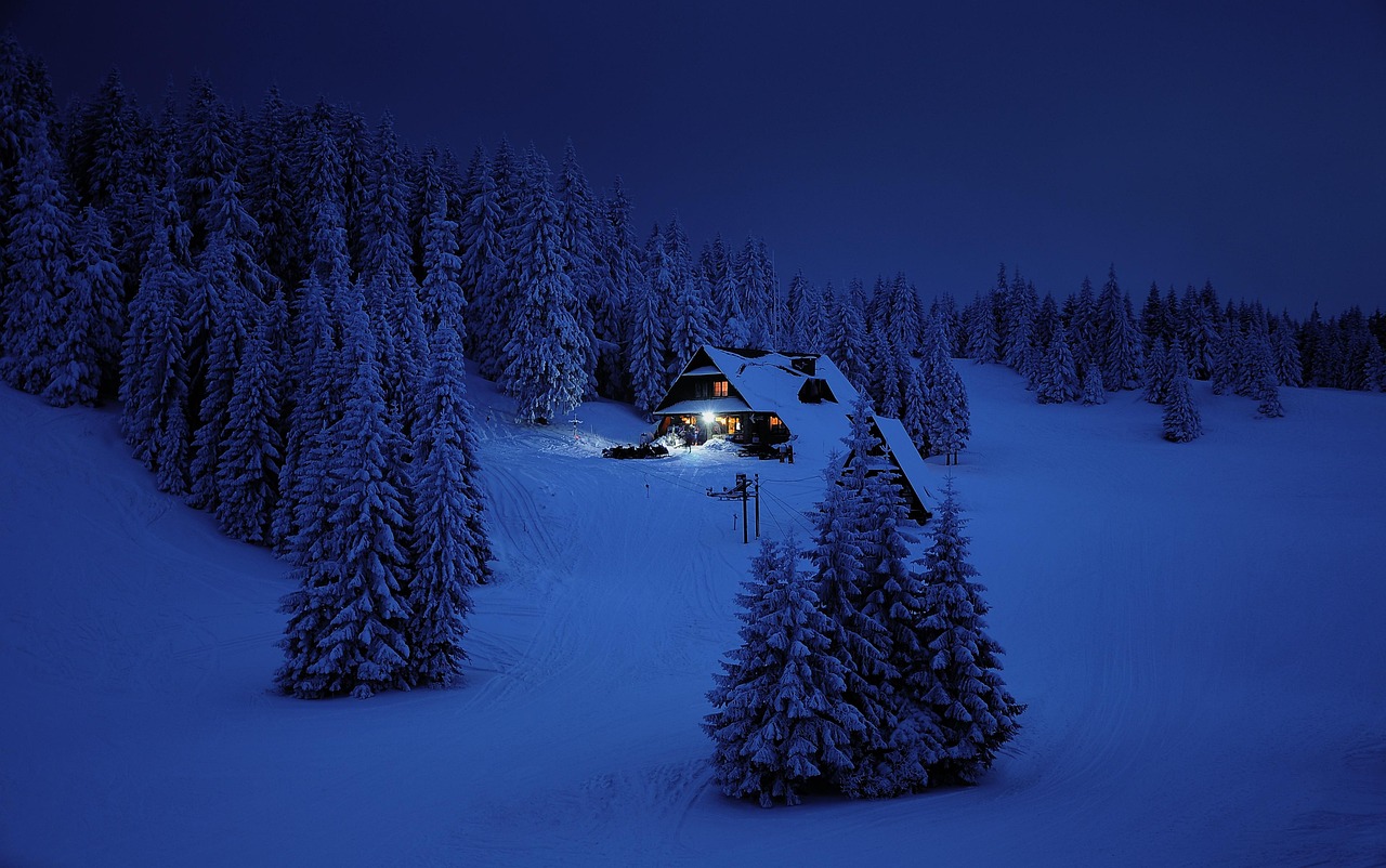 A house glowing at night while the hills around it are dark